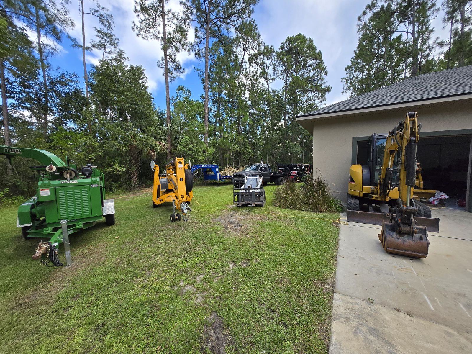 Wood chipper, boom lift, and excavator for tree removal in Eustis, FL